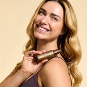 Model holding Face Glow Advanced Hydrating SPF & Tan Cream 